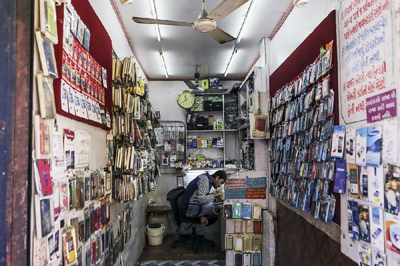 A man repairs a mobile phone at a repair store in the Relief Road area of Ahmadabad in Gujarat, India. India has a dozen wireless carriers — more than in any other country.