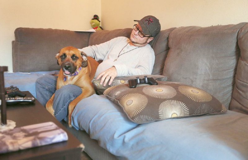 Justin Six pets his service dog, Maggie, at his home in Springdale on Dec. 17. Six, an Army veteran, suffers from post-traumatic stress disorder. He says Maggie will wake him up in the middle of the night when he is having nightmares and also helps him with his anxiety. 