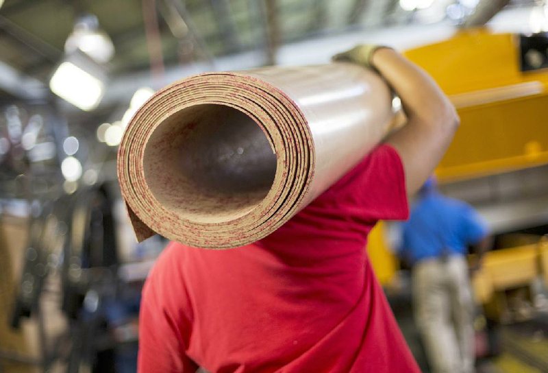 A worker carries a roll of sub-flooring for a school bus at an assembly line at Blue Bird Corp.’s manufacturing center in Fort Valley, Ga., in September. U.S. manufacturing slowed in December, a report Monday said.