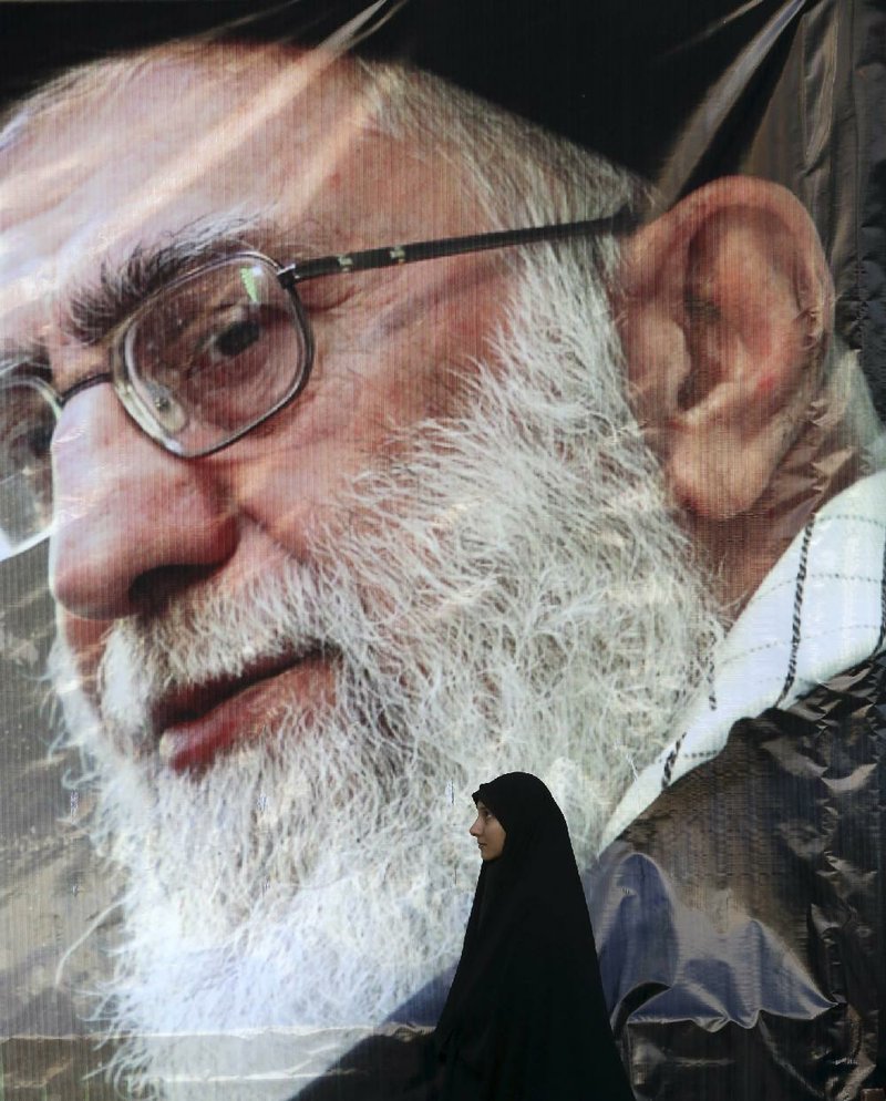 An Iranian woman stands Monday under a portrait of Supreme Leader Ayatollah Ali Khamenei in Tehran. Tension between Saudi Arabia and Iran has the potential to lead to lower oil prices, experts say.