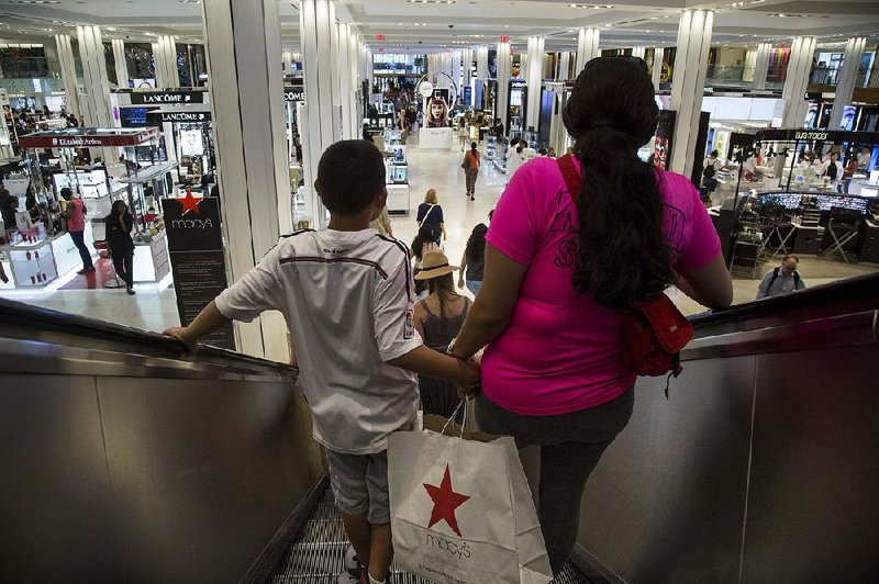 Shoppers ride an escalator at a Macy’s Inc. department store in New York City, in August. 