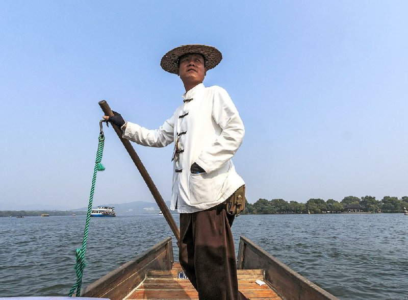A boatman steers during a tour on Hangzhou’s West Lake. There are numerous temples, pagodas, gardens, and artificial islands within the lake. West Lake has influenced poets and painters throughout Chinese history for its natural beauty and historic relics. It was made a UNESCO World Heritage Site in 2011.