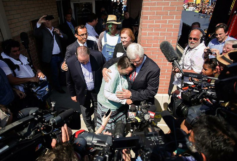 Surrounded by cameras and reporters, Mike Huckabee (front left, head bowed) joins Rowan County, Ky., Clerk Kim Davis (center) and others, including Janet Huckabee (right center), after Davis was released from jail Sept. 8 in Grayson, Ky.