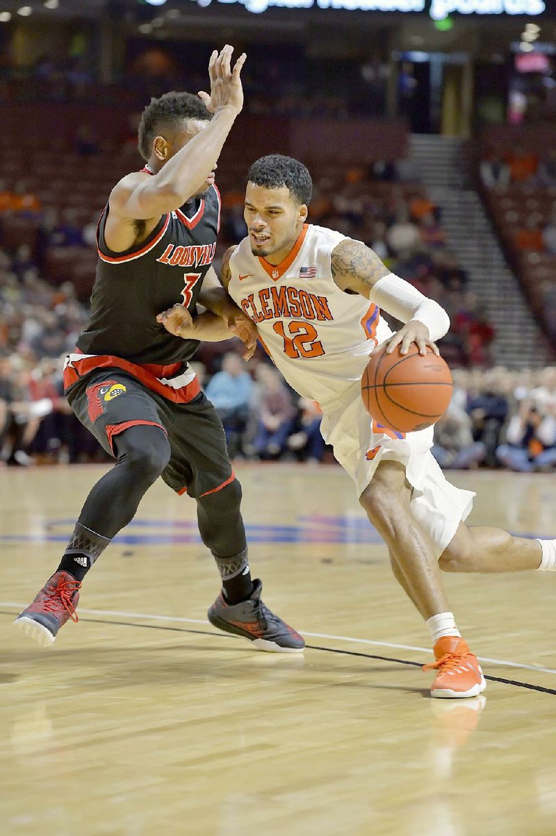 Clemson guard Avry Holmes (right) pushes past Louisville defender Trey Lewis during the first half of Sunday’s game in Greenville, S.C. Holmes fi nished with 16 points and Clemson won 66-62.