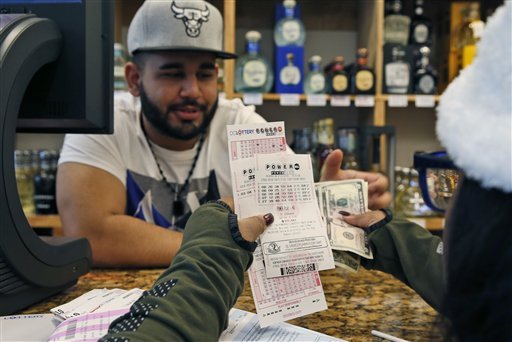 Samir Akhter, the owner of Penn Branch Liquor, exchanges money for Powerball tickets Saturday, Jan. 9, 2016, in Washington. 