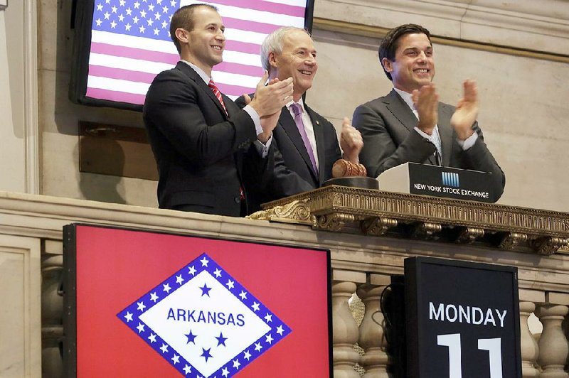 CORRECTS LAST NAME TO HUTCHINSON, NOT HUTCHINS - Arkansas Gov. Asa Hutchinson, center, is applauded by New York Stock Exchange President Tom Farley, right, and Mike Preston, Arkansas Executive Director of Economic Developement, as he rings the New York Stock Exchange opening bell, Monday, Jan. 11, 2016. U.S. stocks are opening higher as the market shakes off the latest drop in China. (AP Photo/Richard Drew)