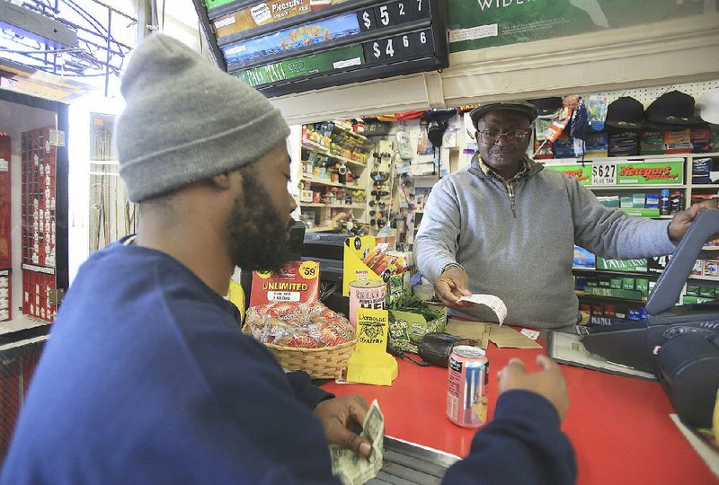 Eric Ward (left) buys a lottery ticket from manager Harold Tunious on Monday afternoon at the D & J Mini Mart at 18th and Main streets in North Little Rock.