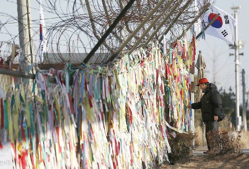 A man reads messages on ribbons hanging on a fence wishing for the reunification of the two Koreas on Monday at the Imjingak Pavilion near the border village of Panmunjom, which has separated the two Koreas since the Korean War, in Paju, north of Seoul, South Korea.