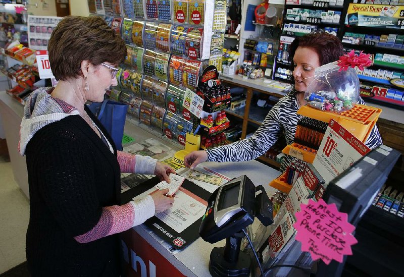 Diane Morrow purchases Powerball tickets Tuesday from Rhonda Burke at Fast Trax in the Southgate Shopping Center in Fayetteville. 