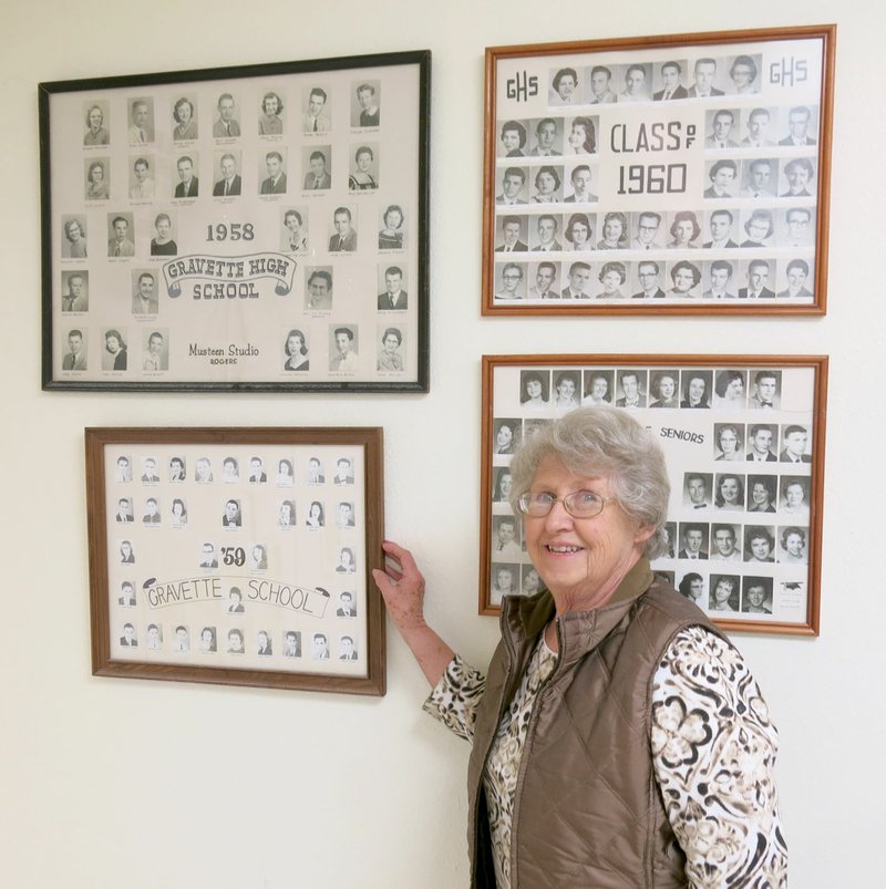 Photo by Susan Holland Louise Evans, who is one of the five persons who have been on the Gravette historical museum commission since its beginning in 1995, shows one of the composite senior class pictures she mounted for display in the museum&#8217;s annex. Obtaining and restoring the old class photos for the museum&#8217;s collection has been Louise&#8217;s special project while on the commission. Just above the photo she is pointing to is the photo of her graduating class, the class of 1958.