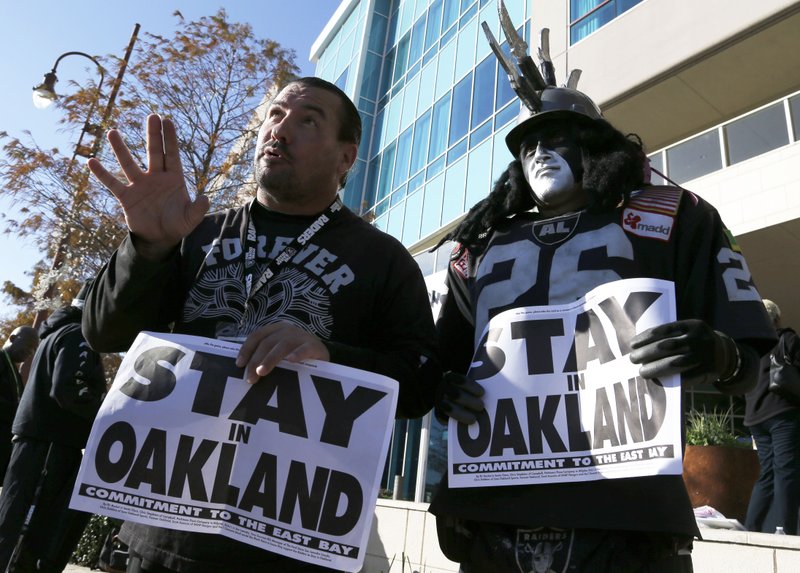 Oakland Raiders fans Griz Jones, left, and Ray Perez make their case for keeping the NFL football team in Oakland outside the hotel where NFL owners are meeting Tuesday, Jan. 12, 2016, in Houston to discuss possible relocation to Los Angeles. (AP Photo/Pat Sullivan)