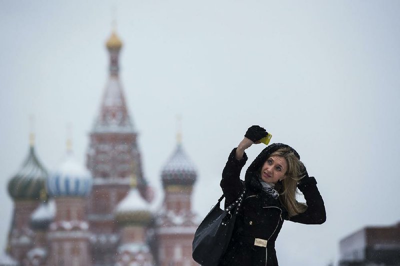 A woman takes a selfie in the snow Wednesday in Moscow’s Red Square. The Russian economy, which relies on its oil and gas industry, is slowing because of a drop in global energy prices. 
