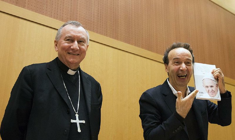 Italian actor Roberto Benigni, right, and Vatican Secretary of State Cardinal Piero Parolin pose for photographers during the official launch of Pope Francis' first book 'The Name of God is Mercy ', in Rome, Tuesday, Jan. 12, 2016.  