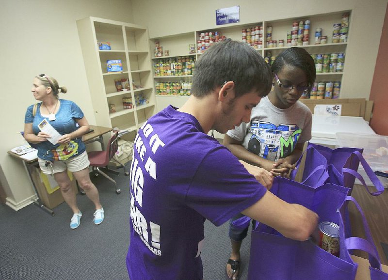Jayla Hobbs (right), 21, of Lonoke and Jake Farmer, 20, of Rogers put food in baskets for Regina Hall at the University of Central Arkansas food pantry in Conway. 