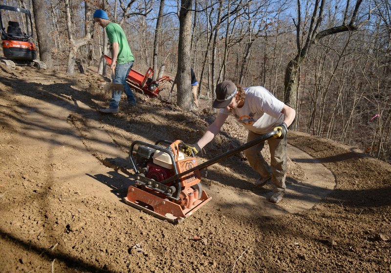 Dalton Campbell (left) and Matt Torvinen with Rock Solid Trail Contracting, based in Copper Harbor, Mich., helps build new trail Thursday as crews work to construct a network of singletrack trail in Bella Vista. For more photos, go to www.nwadg.com/photos. 