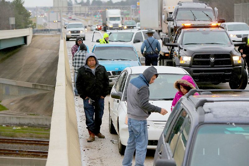 Drivers wait to be towed Monday morning from a six-vehicle wreck on Interstate 30 westbound on the University Avenue overpass in Little Rock. Icy conditions on area overpasses caught many drivers by surprise.