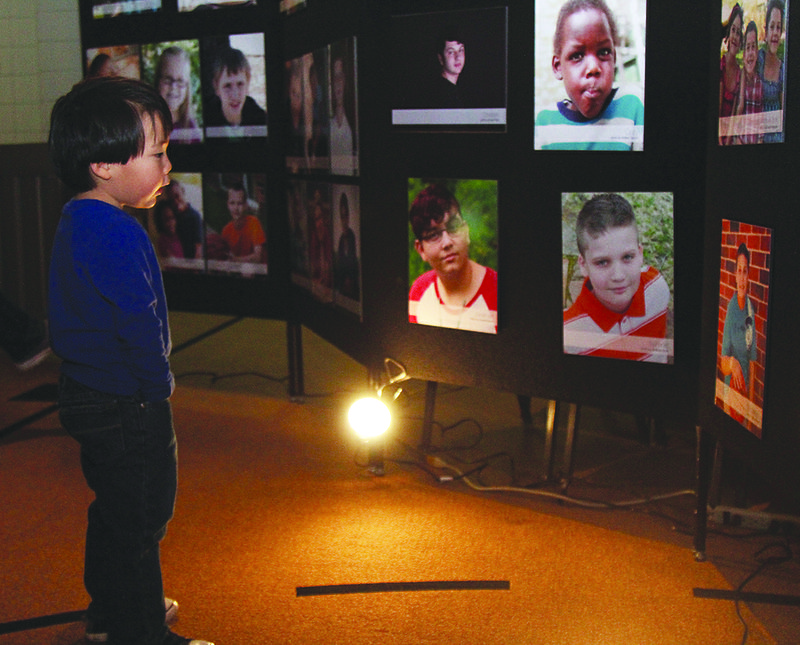 News-Times/Faith Lightsy: Three-year-old Lennox Little looks at other chidlren on the wall at Monday's Arkansas Heart Gallery reception.  Lennox attended the event with his mom, Laura.