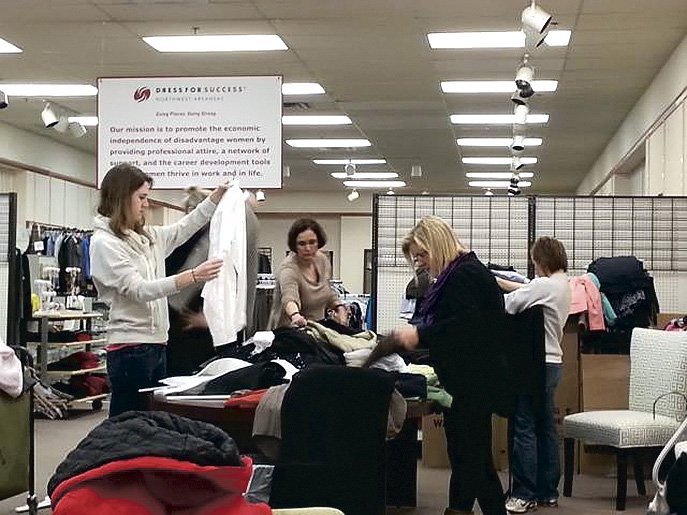 Volunteers sort donated clothing at the Dress for Success Northwest Arkansas Boutique in Rogers. The nonprofit organization will hold a wine tasting fundraiser Feb. 2 at the boutique. 