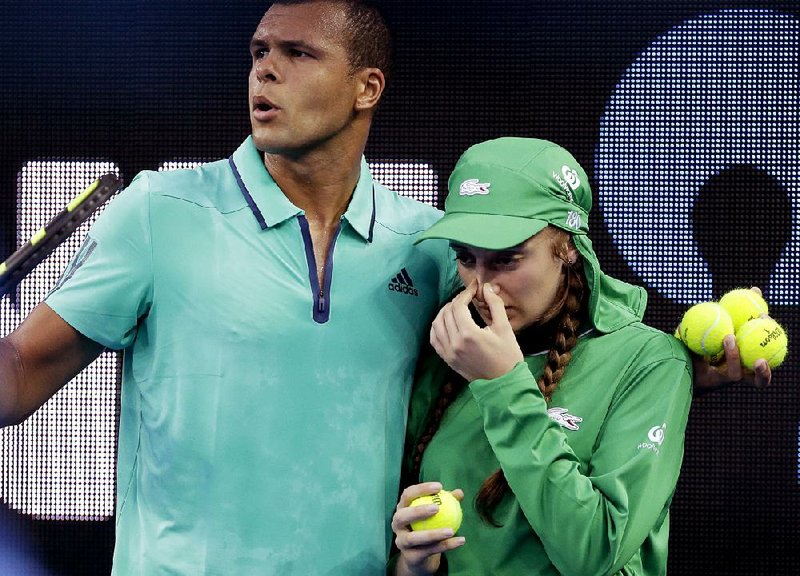 French tennis player Jo-Wilfried Tsonga helps a ball girl off the court after she was hit in the face with a ball during a second-round match against Australian Omar Jasika at the Australian Open in Melbourne on Wednesday. 