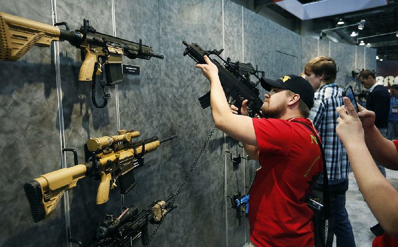 Nolan Hammer looks at a rifle at the Shooting, Hunting and Outdoor Tradeshow in Las Vegas on Tuesday. At the event, Remington Outdoor Co. announced that it will add more than 80 jobs at its Lonoke plant and SIG Sauer will open a Jacksonville manufacturing operation that will employ 50. 