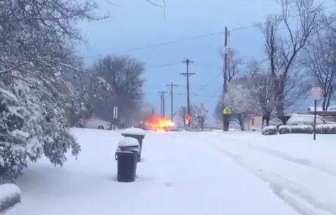 Screenshot from a video showing a car catching fire after getting stuck in snow in North Little Rock.