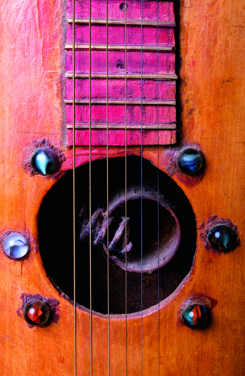 Marbles surround the soundhole of a guitar Stilley made for his niece Malinda Miller Fitch. Inside the guitar you can see the pipe and string arrangement that lends it a unique resonator sound.