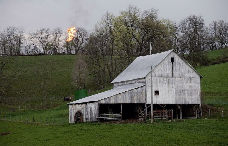 A flame from a flare stack on a natural-gas rig rises behind a barn in Washington County, Pa., in this file photo. Federal rules proposed Friday would clamp down on oil companies that burn off natural gas on public land. 