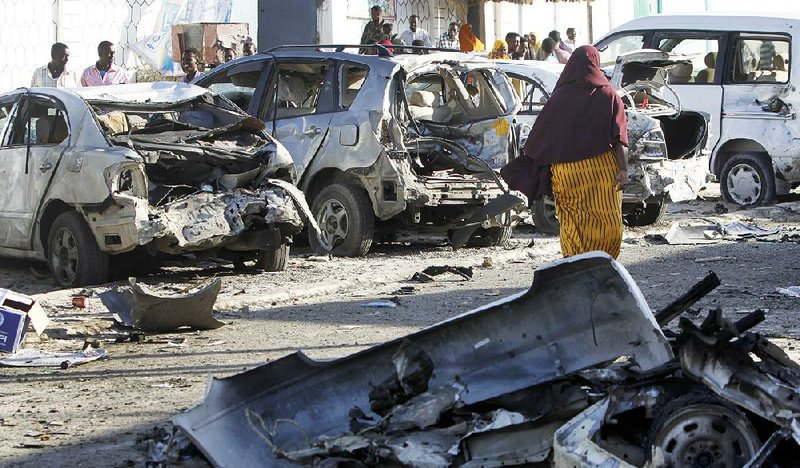 Somalis walk past bomb-damaged vehicles outside a beachfront restaurant Friday after an attack the day before in Mogadishu. 
