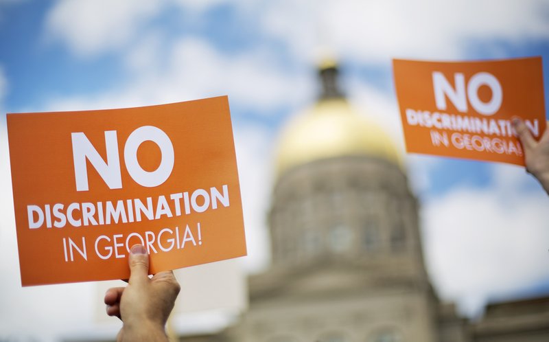 In this March 17, 2015, file photo, protesters hold up signs as the dome of the Capitol stands in the background during a rally against a contentious "religious freedom" bill in Atlanta.