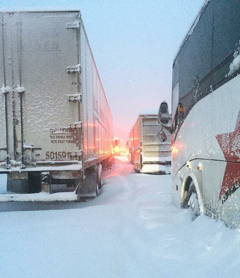 The bus carrying the Duquesne men’s basketball team (right) is shown stuck in the snow on the Pennsylvania Turnpike near Somerset, Pa., on Saturday.