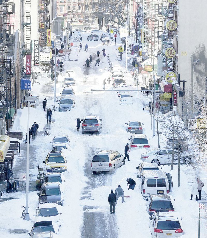 People attempt to dig out their parked cars Sunday in the Chinatown neighborhood of New York after a blizzard that dropped more than 30 inches of snow in some parts of the city.