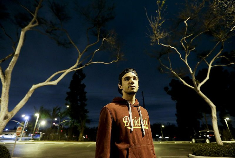 College student Christopher Rael, standing Jan. 19 at California State University, Long Beach, is one of millions of healthy adults facing the choice between signing up for health insurance and facing a fine. 