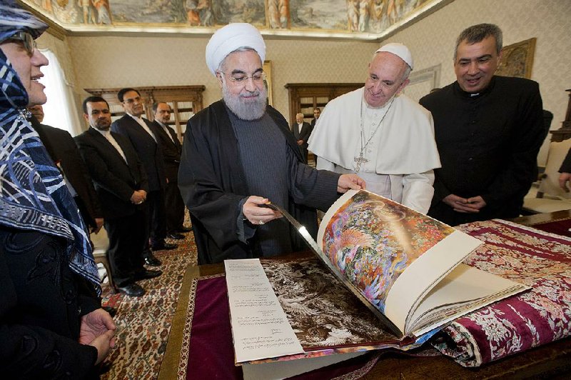 Iranian President Hassan Rouhani leafs through a book Tuesday after presenting it and a Persian rug to Pope Francis during a private audience at the Vatican. Rouhani and the pope met for 40 minutes. Francis called on Iran to play a key role in halting terrorism, and Rouhani asked the pope for prayers.  