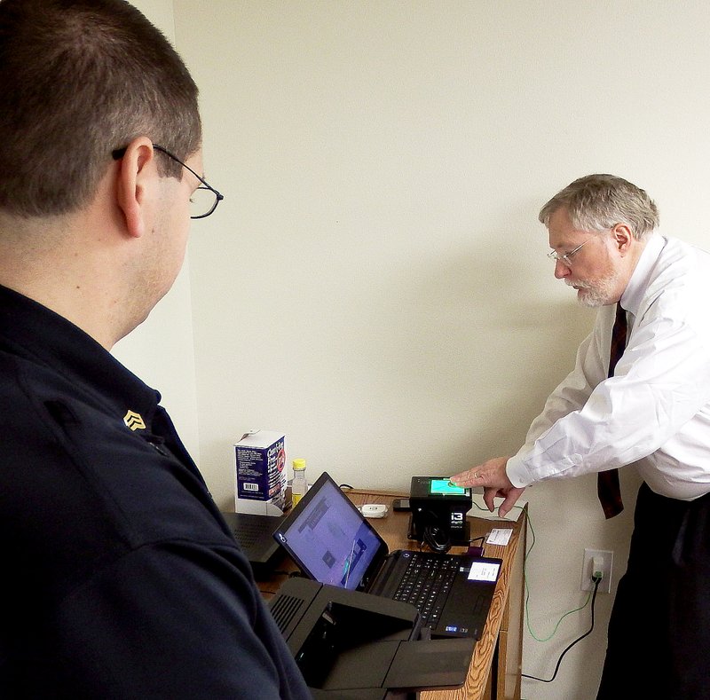 TIMES photograph by Annette Beard Jack Harper, right, president of Secure Outcomes, and developer of Livescan Systems fingerprinting, showed Pea Ridge Police officers, including School Resource Officer John Langham (left), how to operate the Livescan system.