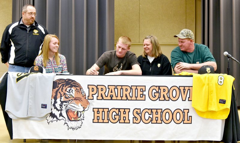 Photo by Shelley Williams/Prairie Grove right-hand pitcher Logan Gragg, center, signs with Connors State during a signing ceremony in his high school cafeteria. His parents are Shawna and Scott Gragg. He&#8217;s coached by Chris Mileham.