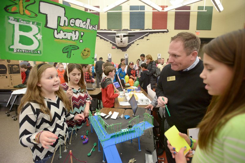 Ella Fisher (from left), Kenzi Lang and Ana Michaelis, all fifth-graders, present their The Natural World playground concept Monday to David Wright, Bentonville Parks and Recreation director, during a science fair-style presentation by students at Bright Field Middle School in Bentonville. Fifth-graders at the school studied playgrounds in their science classes to learn about kinetic energy, with teams then designing their own playground concepts to present to their families and city leaders.