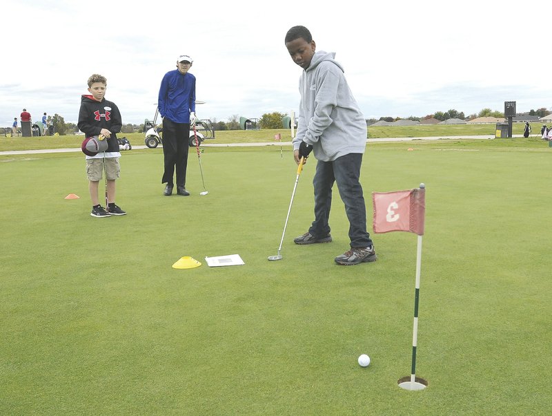 Ira Fielder (from left) Hunter Brown and Xavier Walker practice their putting last October at The First Tee golf school in Lowell. Students learn to play golf, but learn lessons that build character as well, said Bill Rice, a golf coach at First Tee. The group will hold a Super Bowl watch-party benefit Feb. 7.
