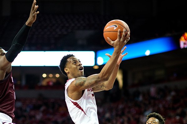 Arkansas' Athlon Bell (5) shoots a basket over Texas A&M's Admon Gilder (3), right, and Danuel House (23), left, in the first half of an NCAA college basketball game in Fayetteville, Ark., Wednesday, Jan. 27, 2016. (AP Photo/Sarah Bentham)
