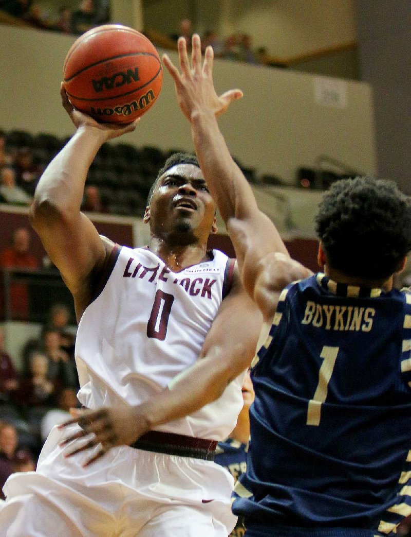 UALR forward Roger Woods (left) puts up a shot over Georgia Southern’s Devonte Boykins during Thursday night’s game at the Jack Stephens Center in Little Rock. Woods scored 13 points to help the Trojans beat the Eagles 80-67 to remain atop the Sun Belt Conference standings.