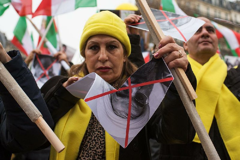 A demonstrator rips apart a picture of Iranian President Hassan Rouhani during a protest in Paris over executions in Iran.