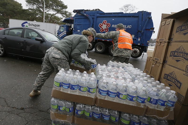 Members of the Michigan National Guard load bottled water at a fire station, Thursday, Jan. 28, 2016 in Flint, Mich. The Michigan Legislature voted Thursday to direct another $28 million to address Flint's water emergency, allocating money for bottled water, medical assessments and other costs in the city struggling with a lead-contaminated supply. (AP Photo/Carlos Osorio) 