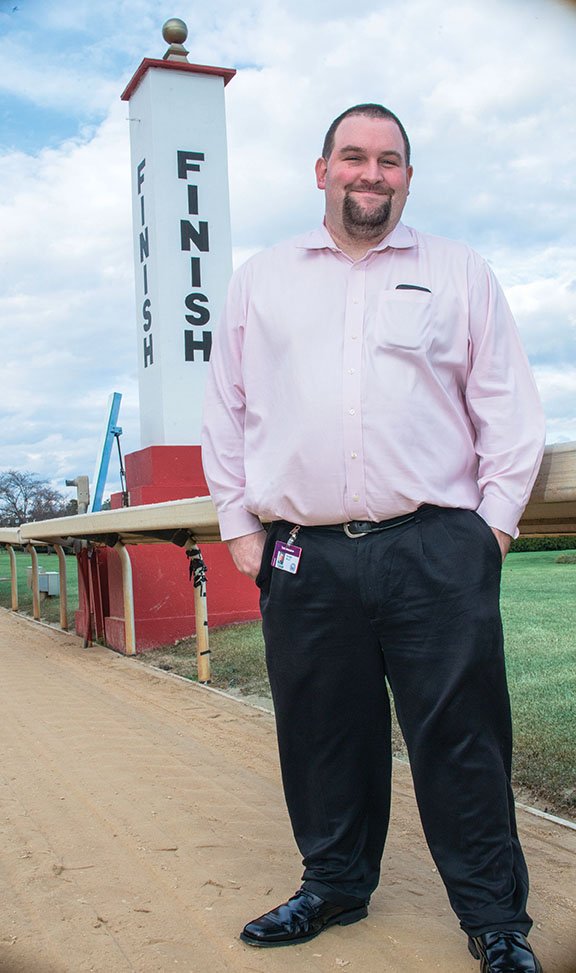 Pete Aiello, the new announcer for Oaklawn, stands on the track by the finish line.