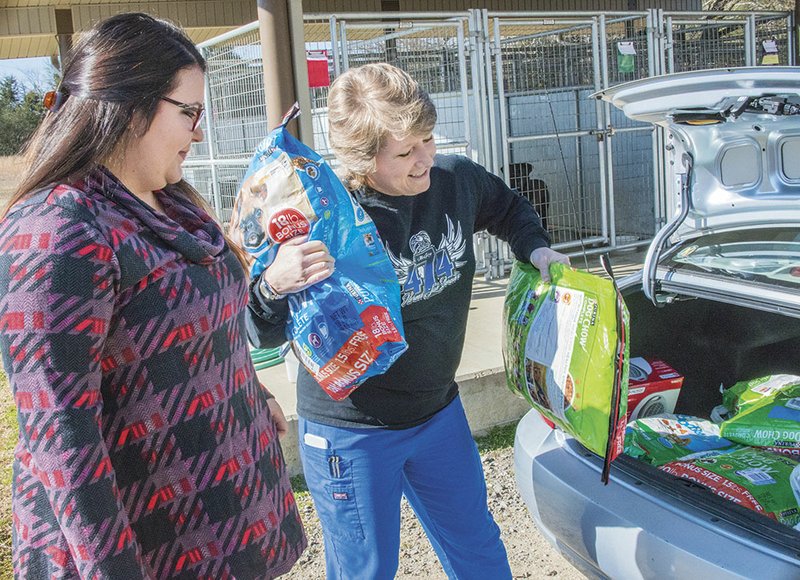Lindsey McGary, left, holds Danny, one of the shelter dogs that she and family representative Robbi Kulik help by donating food and other supplies to the Humane Society of Searcy in honor of fallen officer Will McGary. The shelter’s supervisor, Pam Moorhead, stands with them.