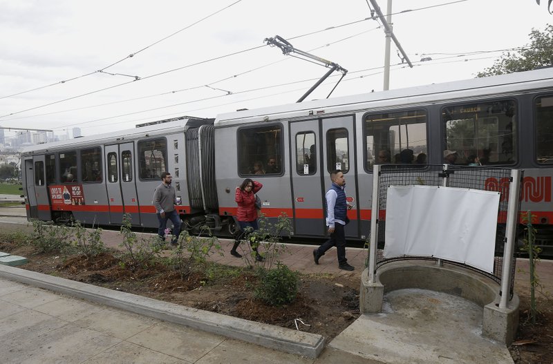 Passengers who exited a San Francisco MUNI streetcar walk past an outdoor urinal across from Dolores Park in San Francisco on Thursday, Jan. 28, 2016. The city's iconic Dolores Park is now home to the city's first open-air urinal, the latest move to combat the destructive scourge of public urination in the City by the Bay. (AP Photo/Jeff Chiu)
