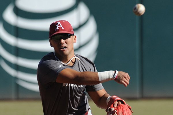 Rick Nomura of Arkansas makes the relay to first Friday, Jan. 29, 2016, during practice at Baum Stadium in Fayetteville.