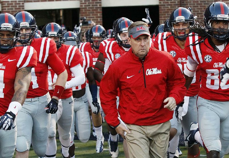 Mississippi football coach Hugh Freeze running onto the field with his team. 