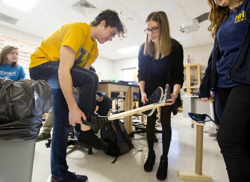 Zander Davidson (left) and Tel Johnson, both seniors at Haas Hall Academy, try out a prosthetic leg Friday made in their bio medical and life sciences class at the Fayetteville campus. The school is hoping to expand to a Springdale campus in The Jones Center.