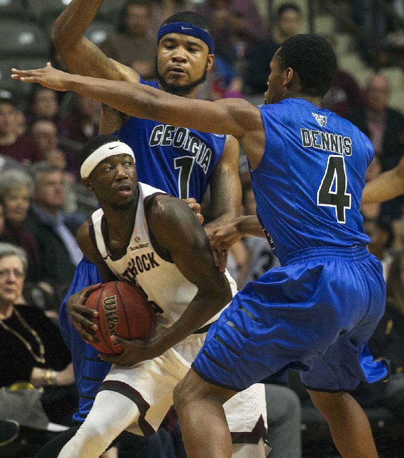 UALR guard Josh Hagins (left) looks for an open teammate in Saturday’s game against Georgia State. The Trojans ran their winning streak to four games by beating the Panthers 63-53.