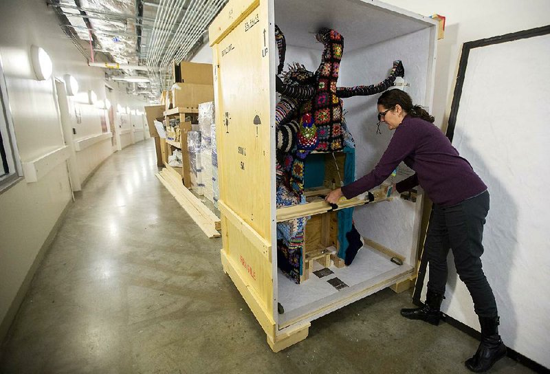 Melanie Fox, associate registrar for exhibitions at Crystal Bridges Museum of American Art, slides a piece of art into a crate to be shipped to other museums. 