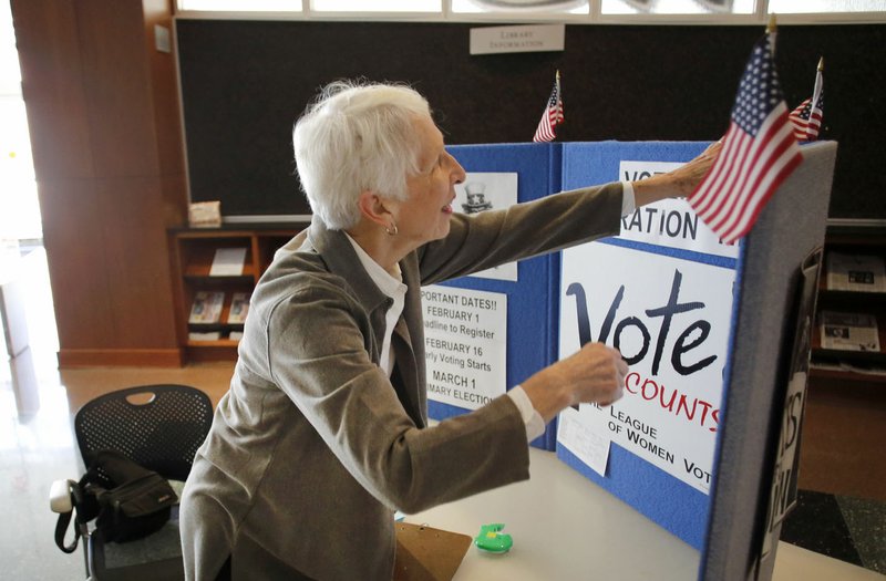 Joyce Hale, with the League of Women Voters of Washington County, prepares her booth Friday at the Fayetteville Public Library. The league will continue to collect voter registration applications and update information today before the Monday deadline for voting in the Preferential Primary Election-Nonpartisan General Election on March 1.